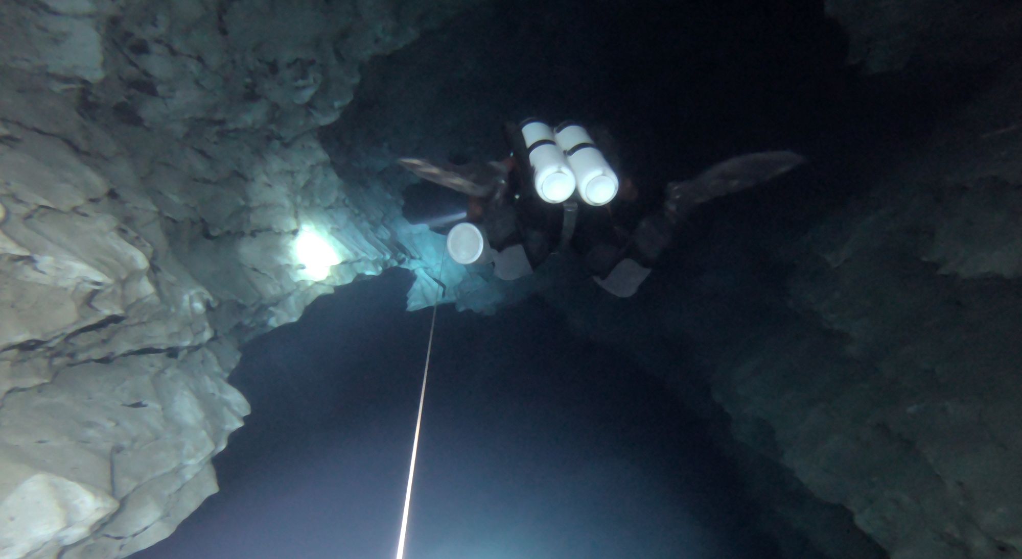 Subacqueo in assetto tecnico con bibombola lungo il filo guida in una grotta allagata